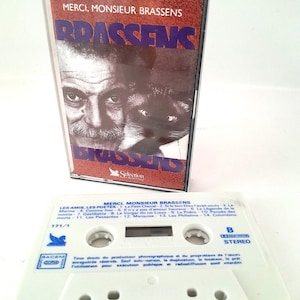 May include: A vintage audio cassette tape featuring the album cover for "Merci, Monsieur Brassens." The cover displays a portrait of a man and a cat. The white cassette tape is labelled with song titles.