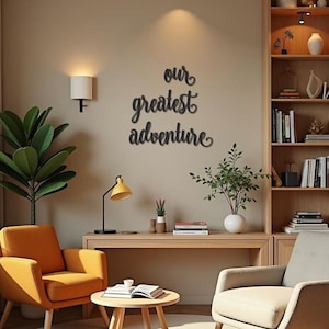 Op de afbeelding: Een gezellige woonkamer met een oranje fauteuil, een houten bureau en een ronde salontafel. De muur toont de tekst "our greatest adventure". Een gele bureaulamp en een boekenkast maken het interieur compleet.