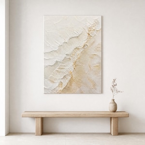 May include: A rectangular canvas painting featuring thick, textured impasto layers in shades of cream, off-white, and soft gold. The composition displays diagonal ridges and raised paint strokes that create a sense of depth and movement across the surface.