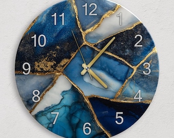 Puede incluir: Reloj de pared redondo con un diseño abstracto azul y blanco, acentuado con líneas doradas. La esfera del reloj presenta números plateados y manecillas doradas. Una pieza decorativa para la decoración del hogar.