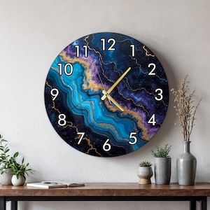 May include: A round wall clock featuring a swirling abstract pattern of deep blue, purple, and turquoise colors with gold veining. The clock face displays large white Arabic numerals from 1 to 12 and has thin gold-colored hour and minute hands.