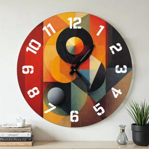 Könnte beinhalten: Eine runde Wanduhr mit einem farbenfrohen abstrakten Design. Das Zifferblatt zeigt geometrische Formen in Rot, Orange, Gelb, Schwarz und Blau. Weiße Zahlen markieren die Stunden. Die Zeiger der Uhr sind schwarz.