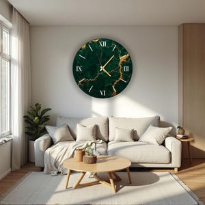 May include: A large, round wall clock with a green marble design and gold accents. Roman numerals mark the hours, and gold hands indicate the time. The clock is mounted on a white wall in a living room setting.