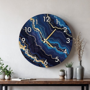 May include: A round wall clock featuring a deep blue and navy marbled pattern with gold-coloured veins. The clock face displays white Arabic numerals from 1 to 12 and includes two gold-coloured hands for indicating the hour and the minute.