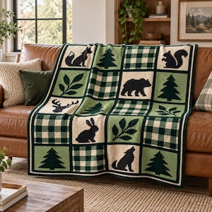 May include: A crochet blanket featuring a grid pattern of alternating squares. The squares display dark green and cream buffalo plaid, solid light green with dark green silhouettes of pine trees, leaves, a bear, a fox, a squirrel, a deer, a rabbit, and a wolf.
