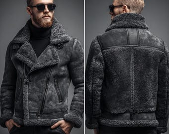 May include: A charcoal gray shearling jacket with a wide collar, asymmetrical zipper, and shearling lining. The jacket features a rugged, distressed appearance and is shown from the front and back.