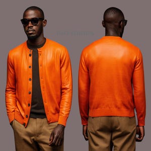 Op de afbeelding: Een feloranje vest met lange mouwen en knoopsluiting, gedragen over een donkergrijs shirt en een beige broek. Het vest heeft een ronde halslijn, geribbelde boorden en een rij donkere knopen. Het beeld toont zowel de voor- als de achterkant.