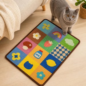 May include: A rectangular area rug featuring a grid of twelve colourful squares with various icons including a yellow pinwheel, a rainbow, a white flower, a red strawberry, a brown mushroom, a blue milk carton, a blue cat head, and a lemon.