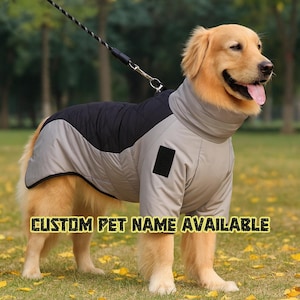 Puede incluir: Un Golden Retriever con un abrigo acolchado gris y negro con cuello alto. El abrigo tiene un parche negro y el texto "CUSTOM PET NAME AVAILABLE" en amarillo.