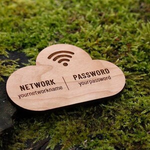 May include: A wooden cloud-shaped sign with engraved text for network and password information. The sign includes a Wi-Fi symbol and is set against a backdrop of green moss.