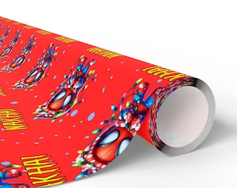 May include: Red wrapping paper featuring a repeating pattern of a Spider-Man mask decorated with Christmas lights. The word "KHAH!" is printed in yellow. The paper is rolled up, showing the silver interior.