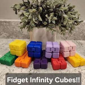 May include: A collection of colorful Fidget Infinity Cubes in various colors, including yellow, green, orange, blue, purple, pink, and red. The text "Fidget Infinity Cubes!!" is displayed at the bottom of the image.