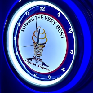 Puede incluir: Un reloj redondo e iluminado con un diseño azul y blanco. La esfera del reloj presenta un personaje de cono de helado y las palabras "SERVING THE VERY BEST". El reloj tiene un borde de neón azul, probablemente para Mister Softee.