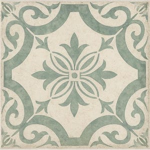 May include: Square tile with a cream-colored background and a repeating teal floral pattern. The design features stylized leaves and scrollwork, creating a symmetrical, decorative motif. The tile has a slightly aged, textured appearance.
