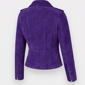 May include: A striking purple suede jacket in a biker style. It has a notched collar, an asymmetrical zip, and zipped cuffs. The jacket is tailored with vertical seams for a flattering fit. The colour is a rich, deep purple.