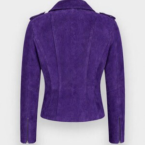 May include: A purple suede biker jacket. It has a notched collar, shoulder epaulettes, and zipped sleeves. The back of the jacket has vertical seams for a tailored fit. The jacket is a vibrant shade of purple.