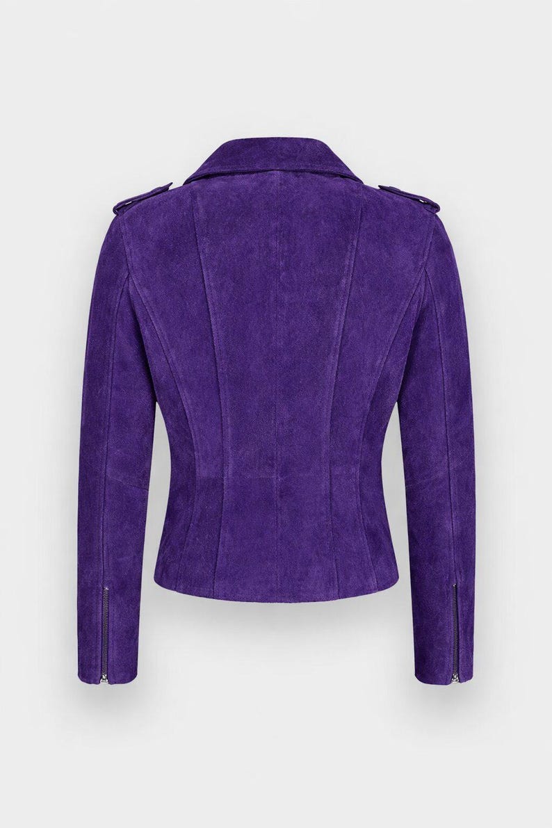 May include: A purple suede biker jacket. It has a notched collar, shoulder epaulettes, and zipped sleeves. The back of the jacket has vertical seams for a tailored fit. The jacket is a vibrant shade of purple.