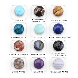 May include: A collection of twelve polished gemstone spheres, each set on a clear square base. The gemstones include opalite, agate fossil, picture jasper, chrysocolla, amazonite, light smoky quartz, crazy lace agate, blue kyanite, blue sand sun sitara, stripe agate, charoite, and blue lace agate.
