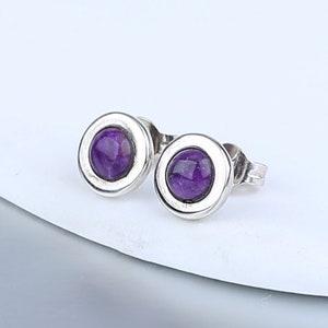 May include: A pair of silver stud earrings with round purple amethyst stones.