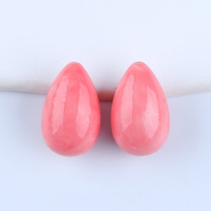 Può includere: Due perle di corallo rosa a forma di goccia. Le perle sono lisce e lucide.