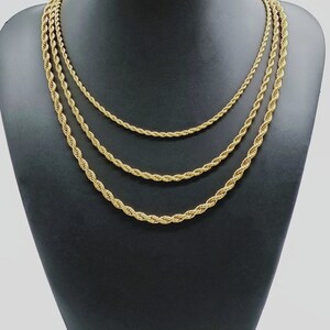 May include: Three gold rope chains of different thicknesses displayed on a black mannequin bust.
