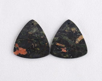 Puede incluir: Dos colgantes triangulares de piedras preciosas con un agujero para ensartar. Los colgantes tienen un color base oscuro con vetas verdes, naranjas y bronceadas. Las piedras preciosas están sobre un fondo blanco.