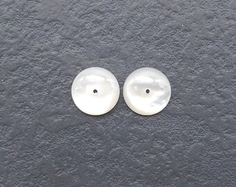 May include: Two white round mother of pearl buttons with a small hole in the center.