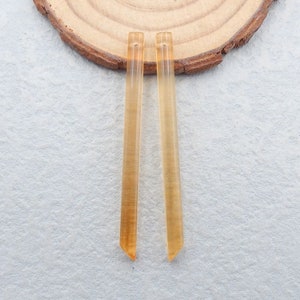 May include: Two long, thin, clear amber glass rods with pointed ends.