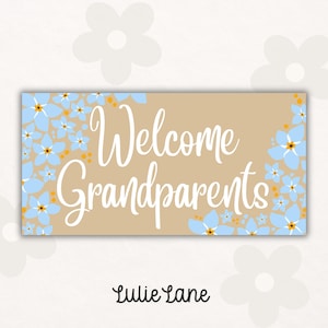 Puede incluir: Un letrero rectangular con fondo beige que presenta flores azul claro con centros amarillos en las esquinas. El texto Welcome Grandparents está escrito en letra blanca en el centro. El texto Lulie Lane aparece en negro debajo del letrero.