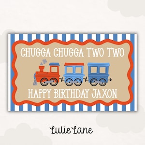 May include: A rectangular sign with a blue and white striped border and a tan center featuring a red and blue train illustration. The text reads CHUGGA CHUGGA TWO TWO and HAPPY BIRTHDAY JAXON in white letters. The brand name Lulie Lane is below.