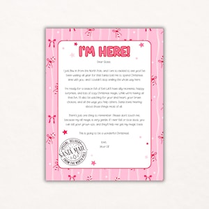 May include: A pink letter with the text "I'M HERE!" in red, with a pink bow and star pattern. The letter is from an elf, delivered by Santa Mail, and contains a holiday message.