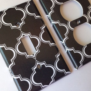 May include: Two black and white patterned wall plates, one for a light switch and one for an outlet. The pattern is a repeating geometric design.