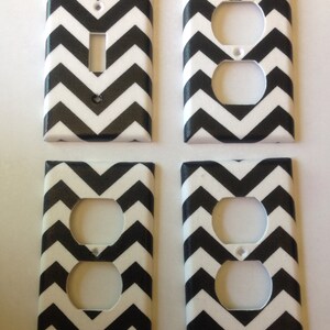 May include: Four black and white chevron patterned wall plates. Two plates are for light switches and two plates are for electrical outlets.