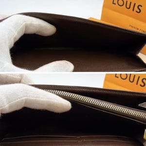 May include: Brown leather wallet with a zipper closure. The interior is a darker brown color. The wallet is open, revealing the inside compartments. The brand name "LOUIS" is visible on the packaging in the background.