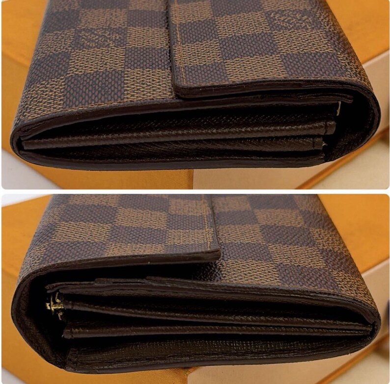 May include: Close-up of a brown and tan checkered pattern wallet. The wallet has a dark brown border and a flap closure. The interior of the wallet is visible, showing multiple compartments for cards and cash.