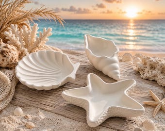 May include: Three white ceramic dishes shaped like sea life, including a scallop shell, a conch shell, and a starfish. The dishes have a smooth, matte finish and are arranged on a weathered wooden surface alongside natural coral and seashells.