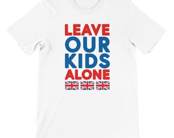 Puede incluir: Camiseta blanca con el texto "LEAVE OUR KIDS ALONE" en letras rojas y azules. Debajo del texto hay tres filas de la bandera de la Union Jack.