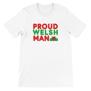 May include: White t-shirt with the text "PROUD WELSH MAN" in red and green block letters. The Welsh flag is displayed next to the word "MAN". The shirt is made of a soft material.