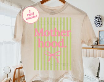 May include: A beige t-shirt featuring the word "Motherhood" in pink, with green vertical stripes behind it. A pink bow is below the word "hood". The text "THECOPYHEIR" is printed below the bow. The shirt is suspended on a wooden hanger.