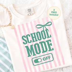 Puede incluir: Camiseta color crema con rayas verticales rosas y el texto "SCHOOL MODE OFF" en verde. Un lazo verde está encima del texto. La camiseta tiene una etiqueta que dice "Comfort Colors".