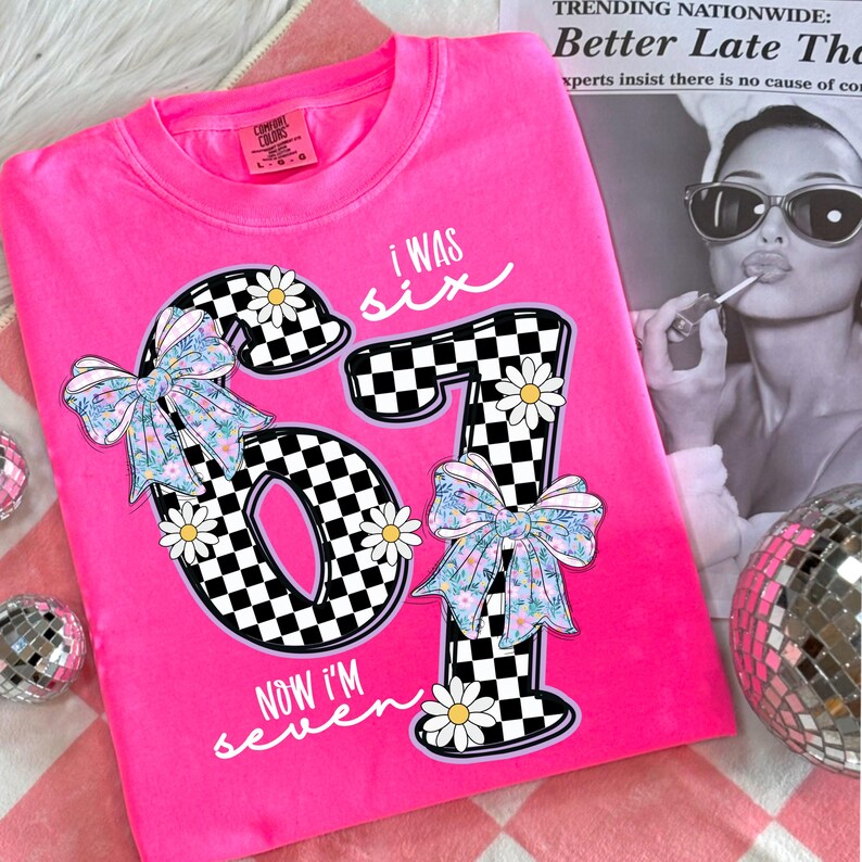 Peut inclure: Un sweat-shirt rose vif Comfort Colors avec l'inscription "I WAS SIX NOW I'M seven". Les chiffres "67" sont dans un motif &agrave; carreaux noir et blanc, d&eacute;cor&eacute;s de marguerites et de n&oelig;uds floraux. Un t-shirt d'anniversaire amusant.