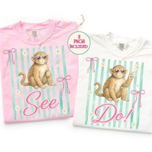 Puede incluir: Dos camisetas Comfort Colors, una rosa y otra blanca, cada una con un mono con gafas de sol. La camiseta rosa dice "See" y la blanca dice "Do!". Ambas tienen un fondo a rayas con lazos y margaritas.