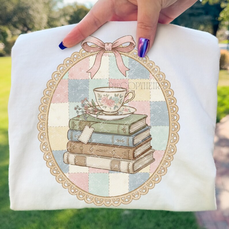 May include: White t-shirt with a vintage design. The design features a stack of books, a teacup, and a bow. The design is framed by a decorative oval border. The text "THECOPYHEIR" is visible.