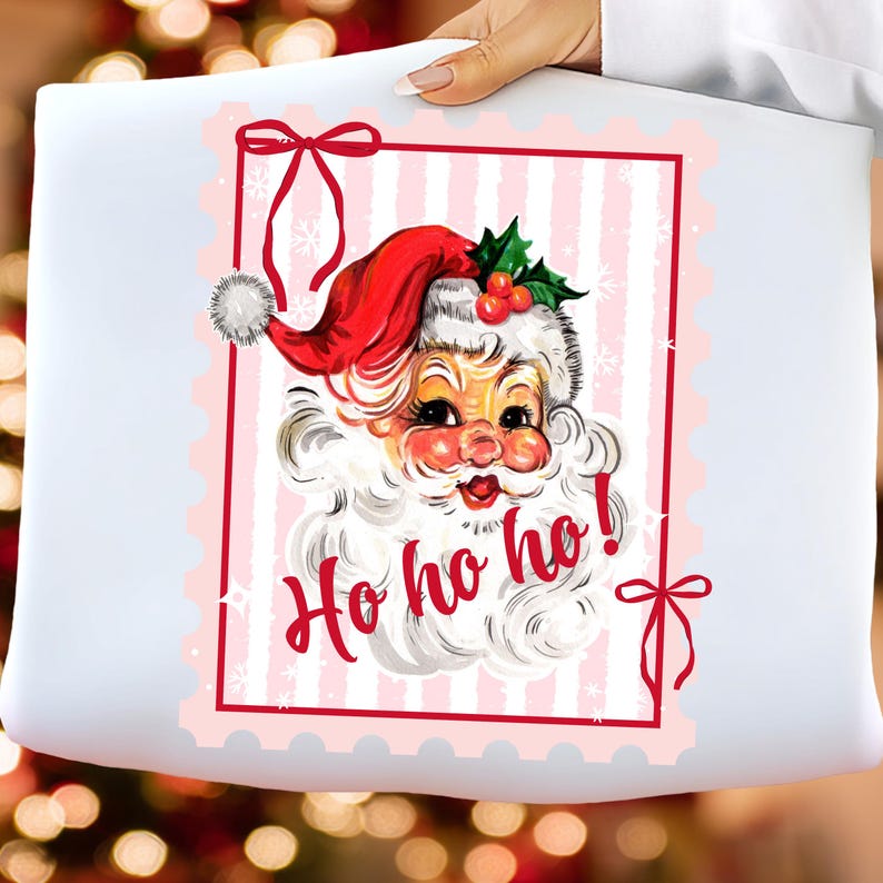 May include: A white pillow with a vintage Santa Claus graphic. The Santa has a red hat, white beard, and rosy cheeks. The words "Ho ho ho!" are written in red script. The design is framed with a red border and pink stripes.