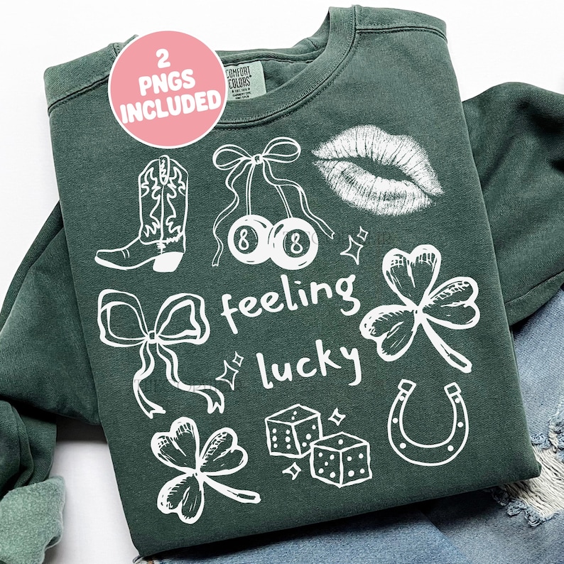 May include: Dark green sweatshirt with white graphic illustrations including a cowboy boot, cherries, lips, shamrocks, dice, a horseshoe, and the words "feeling lucky". A pink circle with the text "2 PNGS INCLUDED" is in the upper left corner.