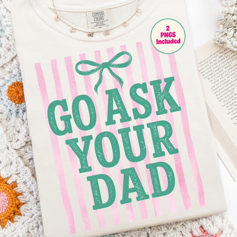 Puede incluir: Camiseta color crema con el texto "GO ASK YOUR DAD" en verde azulado, acentuada con un lazo verde azulado y rayas verticales rosas. Se ve un collar de mariposas y una pegatina "2 PNGs Included".