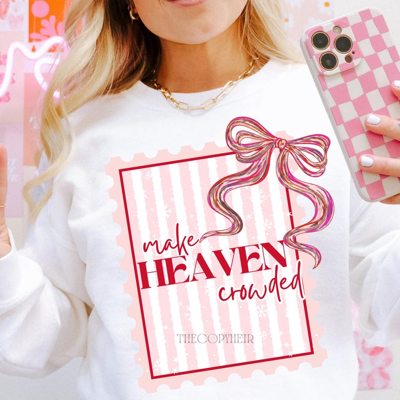 May include: White sweatshirt featuring a pink and white striped design within a red border. The design includes a bow and the words "make HEAVEN crowded" in red. The brand name "THECOPYHEIR" is at the bottom of the design.