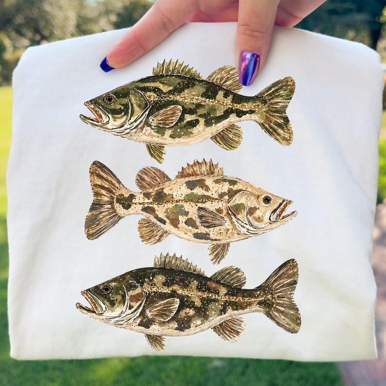 May include: White fabric featuring three watercolor illustrations of bass fish in shades of green, brown, and tan. The fish are detailed with fins, scales, and open mouths, creating a realistic depiction.