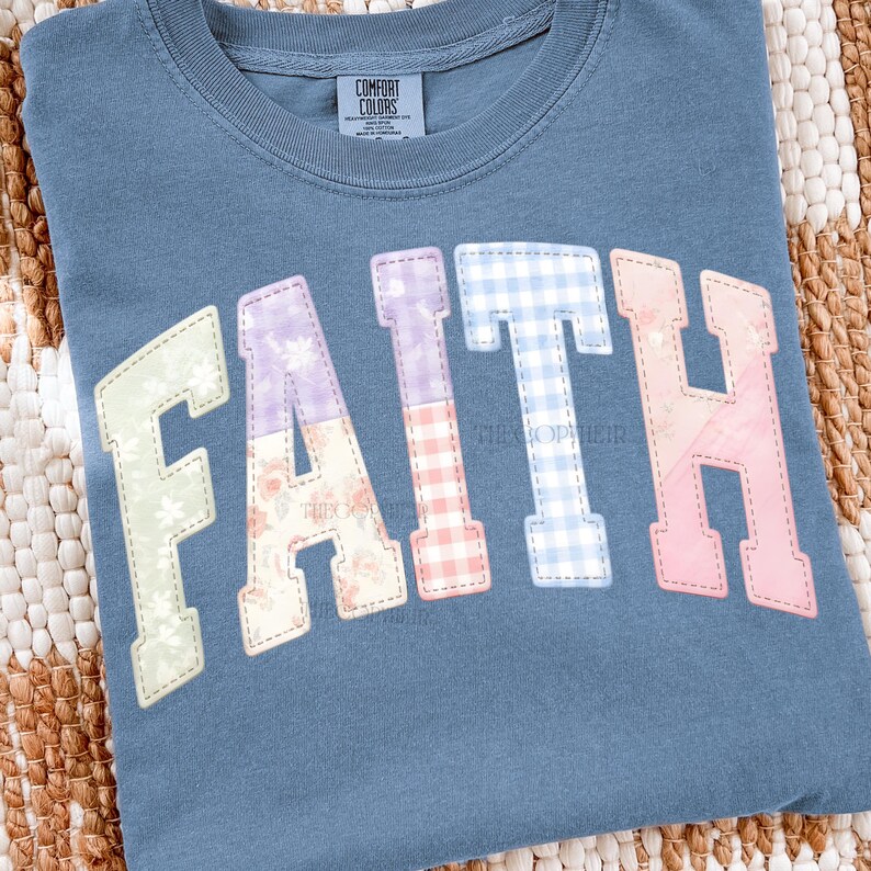 May include: A blue Comfort Colors t-shirt with the word "FAITH" in a patchwork design. The letters are in various pastel colors and patterns, including floral and gingham prints. The shirt has a crew neck and short sleeves.