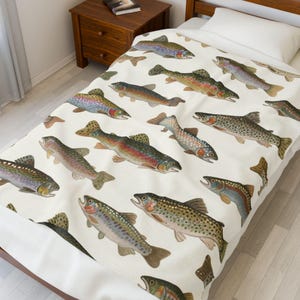 May include: A white bedspread featuring a repeating pattern of colorful fish illustrations. The fish vary in size and color, with details like fins, scales, and gills. The bedspread is on a wooden bed frame, with a nightstand and a book visible in the background.